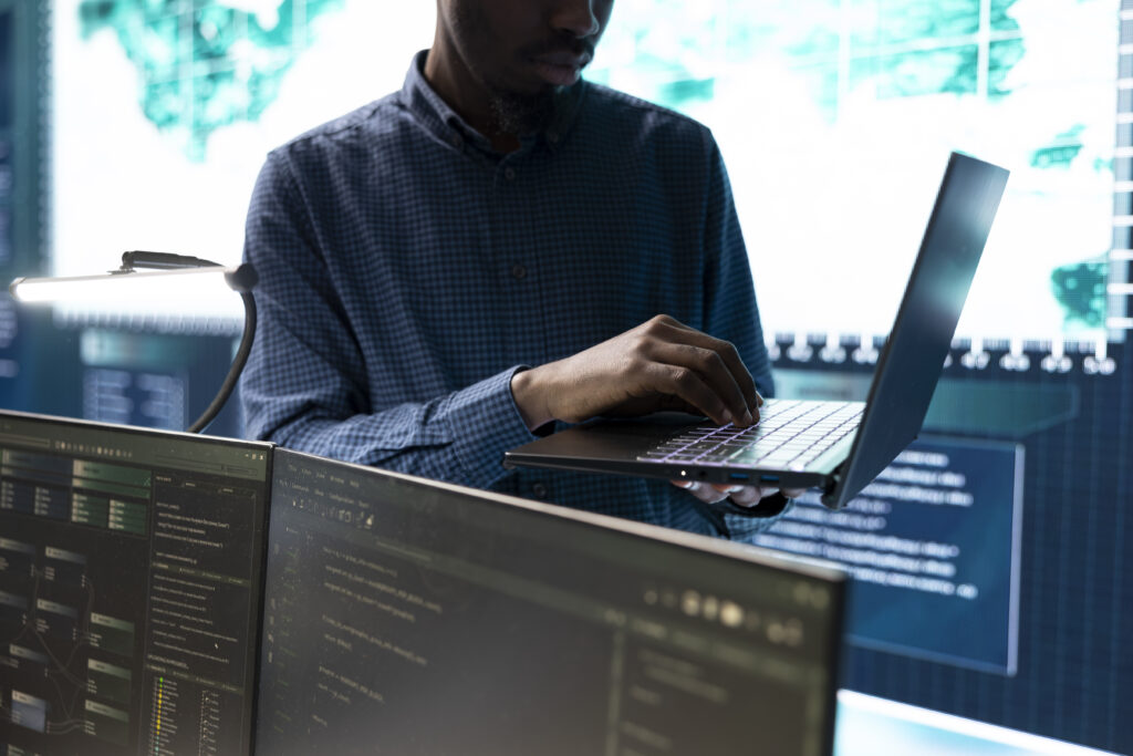 Security analyst using a laptop to investigate threats in a monitoring room