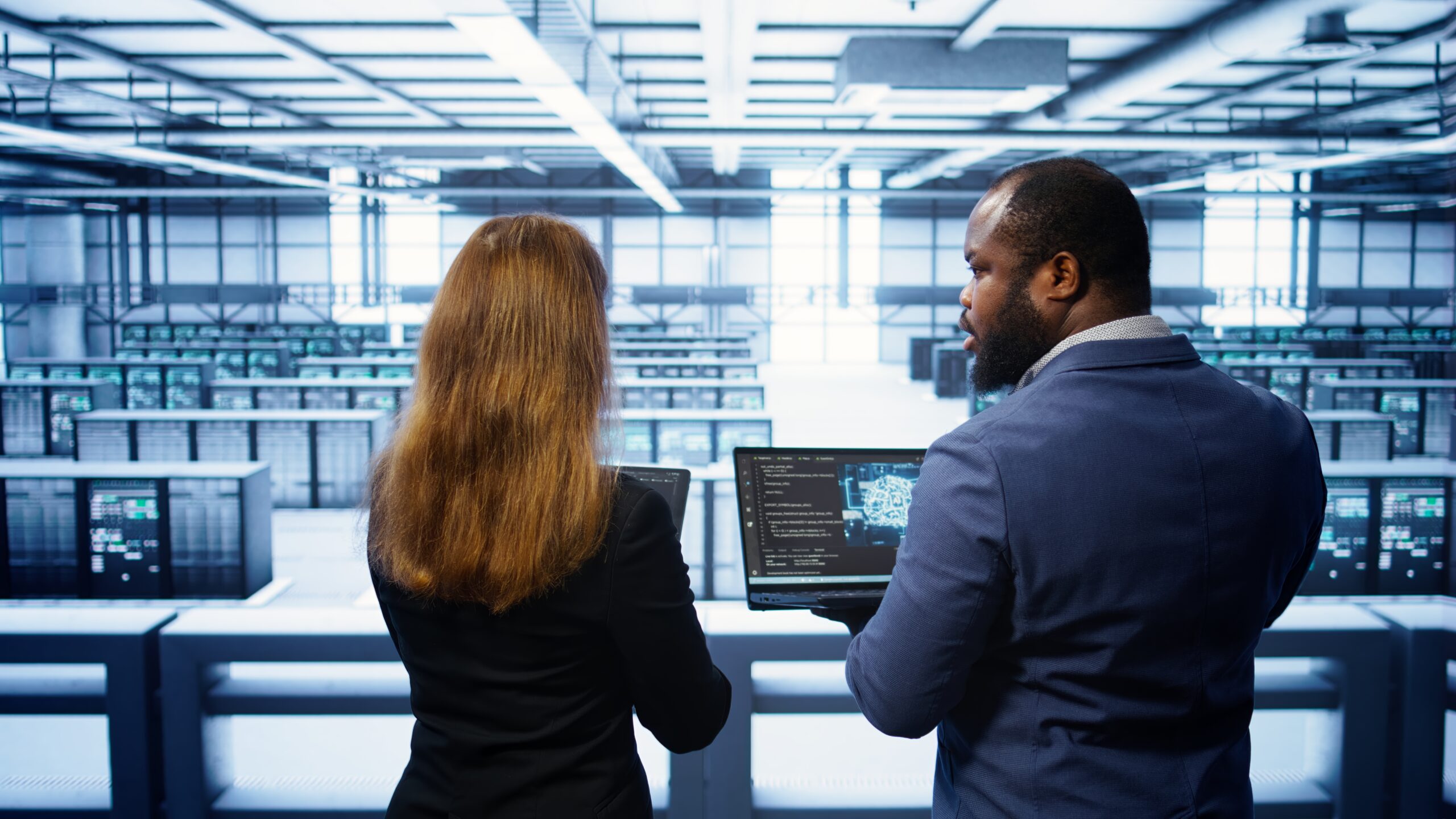 IT engineers reviewing server operations on a laptop in a data centre