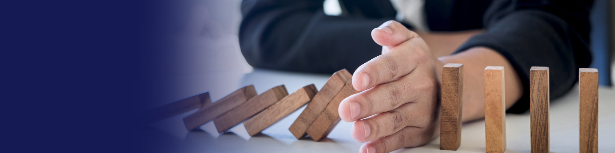 Hand stopping a row of falling wooden dominoes