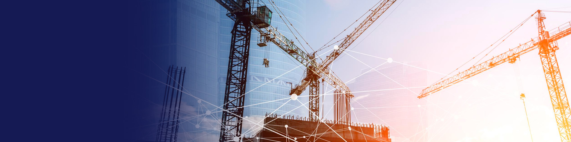Construction cranes over a building site at sunset